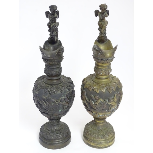 1230 - A pair of early 20thC cast ornamental ewers decorated in relief with fruiting vine and banded putti ... 