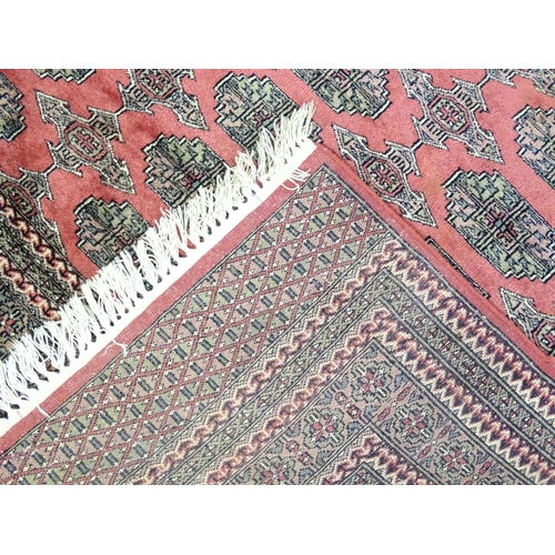 1356 - Carpet / Rug : A rug with salmon ground decorated with repeating motifs and banded borders. Approx. ... 