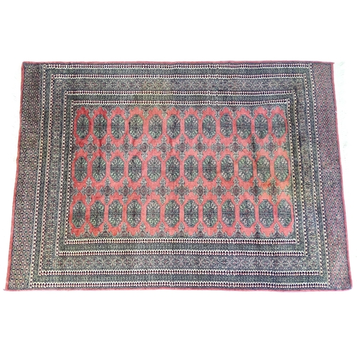 1356 - Carpet / Rug : A rug with salmon ground decorated with repeating motifs and banded borders. Approx. ... 