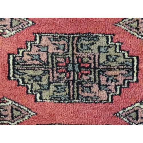 1356 - Carpet / Rug : A rug with salmon ground decorated with repeating motifs and banded borders. Approx. ... 