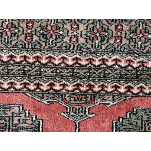 1356 - Carpet / Rug : A rug with salmon ground decorated with repeating motifs and banded borders. Approx. ... 