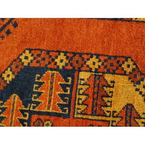 1379 - Carpet / Rug : A rug having orange red ground decorated with repeating geometric, floral and foliate... 