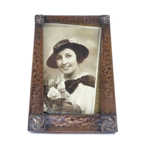 1004 - An Arts & Crafts style easel back photograph frame of tapering form with hammered copper surround an... 