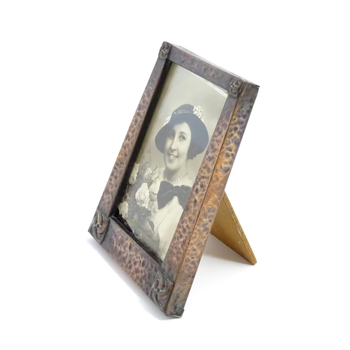 1004 - An Arts & Crafts style easel back photograph frame of tapering form with hammered copper surround an... 