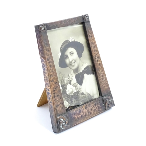 1004 - An Arts & Crafts style easel back photograph frame of tapering form with hammered copper surround an... 