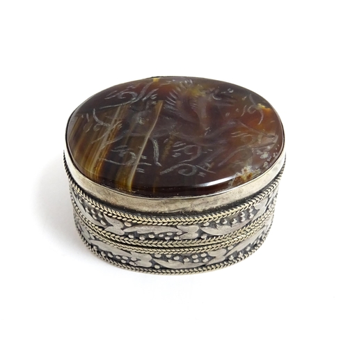 1040 - A white metal pill box of oval form with banded decoration, the top set with agate intaglio depictin... 