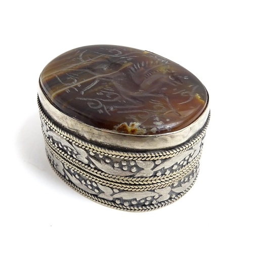 1040 - A white metal pill box of oval form with banded decoration, the top set with agate intaglio depictin... 