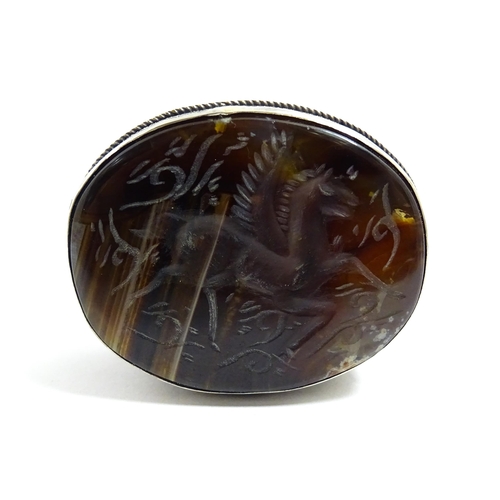 1040 - A white metal pill box of oval form with banded decoration, the top set with agate intaglio depictin... 