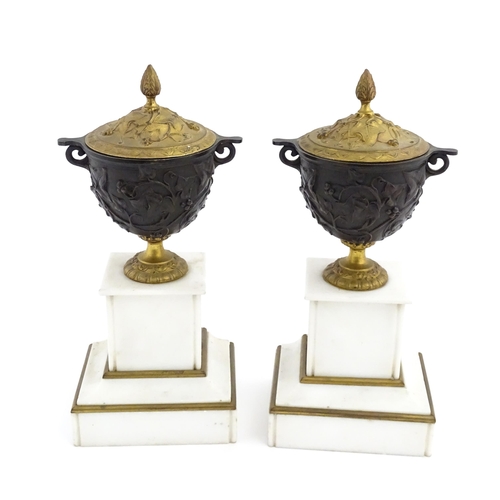 1059 - A pair of late 19th / early 20thC cast lidded urns with scrolling vine decoration, each raised on a ... 