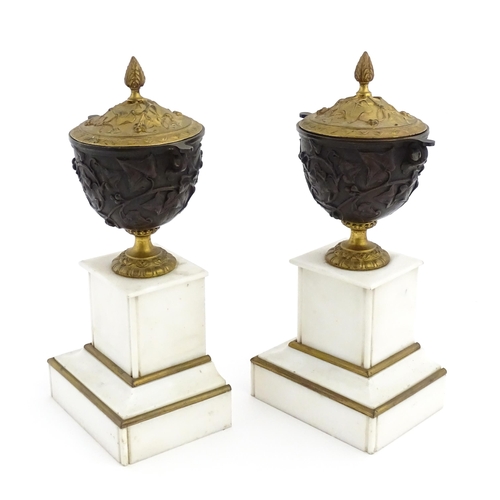 1059 - A pair of late 19th / early 20thC cast lidded urns with scrolling vine decoration, each raised on a ... 