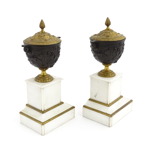 1059 - A pair of late 19th / early 20thC cast lidded urns with scrolling vine decoration, each raised on a ... 