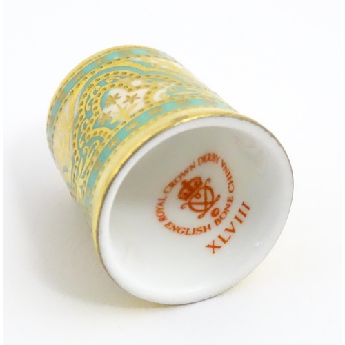 1064 - Fifteen Royal Crown Derby porcelain thimbles in various patterns, displayed on a turned wooden two t... 