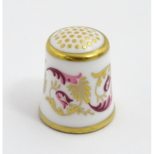 1064 - Fifteen Royal Crown Derby porcelain thimbles in various patterns, displayed on a turned wooden two t... 