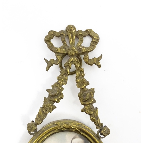 1189 - Two small early 20thC brass frames, one of circular form, the other oval, both with floral swag deco... 