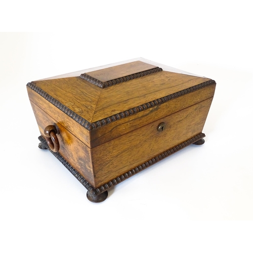 1194 - A Victorian rosewood sewing box / workbox of sarcophagus form with twin ring handles, opening to rev... 