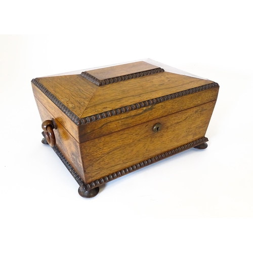 1194 - A Victorian rosewood sewing box / workbox of sarcophagus form with twin ring handles, opening to rev... 