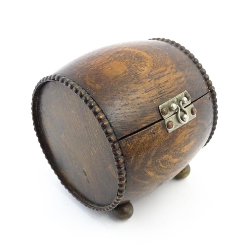 1198 - A 20thC oak cigarette barrel with hinged lid and raised on four feet. Approx. 4 1/4