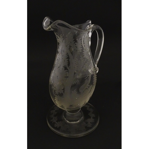 225 - A Victorian glass pitcher / jug with pedestal foot, loop handle and etched a stag and game bird deco... 