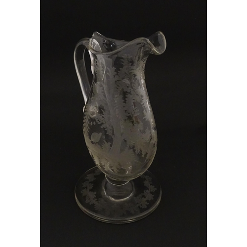 225 - A Victorian glass pitcher / jug with pedestal foot, loop handle and etched a stag and game bird deco... 