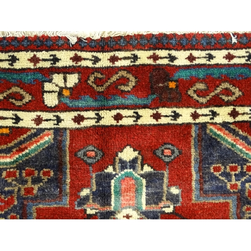 1372 - Carpet / Rug : A  North west Persian Koliahee rug with dark red and blue grounds and central cream g... 