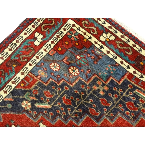 1372 - Carpet / Rug : A  North west Persian Koliahee rug with dark red and blue grounds and central cream g... 