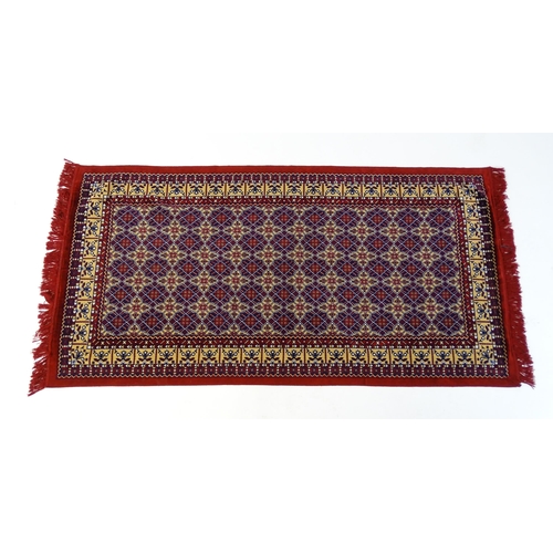 1385 - Carpet / Rug : A red ground rug decorated with repeating floral and geometric motifs. Approx. 79