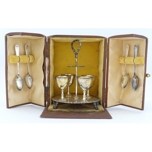 592 - A cased silver plate egg cruet comprising four egg cups, four spoons and a stand. Approx. 8 1/2