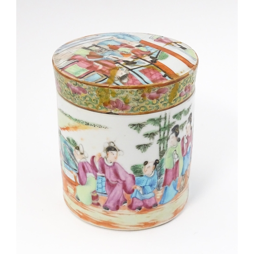 18A - A Chinese / Cantonese famille rose pot and cover depicting figures in an interior. Approx. 4 1/2