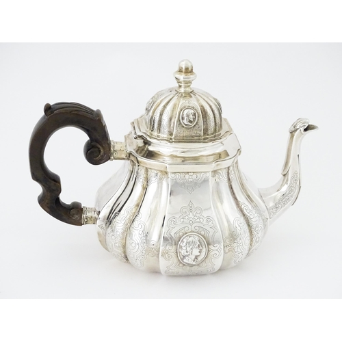 279 - A Victorian silver teapot with engraved decoration and oval figural bust detail. Hallmarked London 1... 