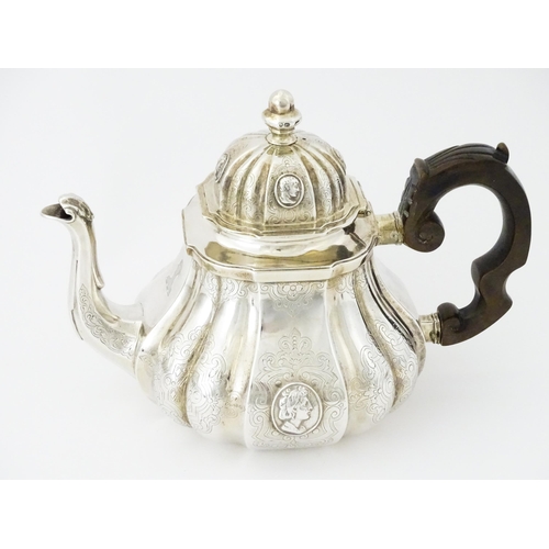 279 - A Victorian silver teapot with engraved decoration and oval figural bust detail. Hallmarked London 1... 