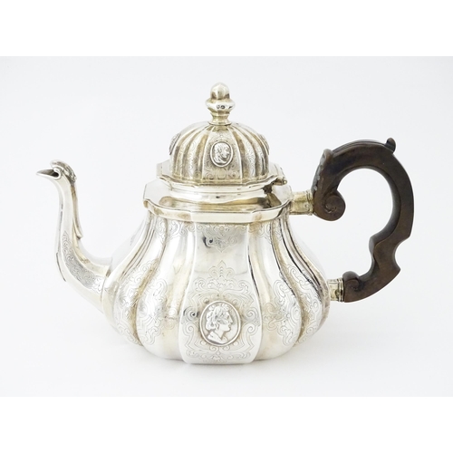 279 - A Victorian silver teapot with engraved decoration and oval figural bust detail. Hallmarked London 1... 