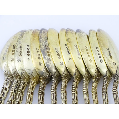 298 - A set of twelve Victorian silver gilt dessert spoons with fruiting vine detail to handles, hallmarke... 