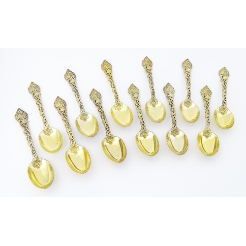 298 - A set of twelve Victorian silver gilt dessert spoons with fruiting vine detail to handles, hallmarke... 