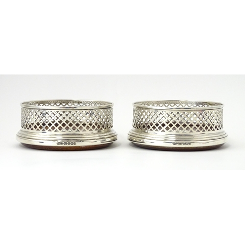 321 - A matched pair of silver coasters with pierced decoration and turned wooden bases, hallmarked Birmin... 