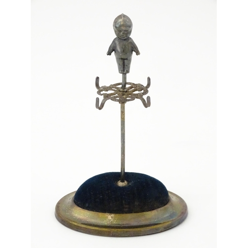 334 - A silver plate hat pin holder / ring tree surmounted by a model of a Kewpie doll. Marked with regist... 