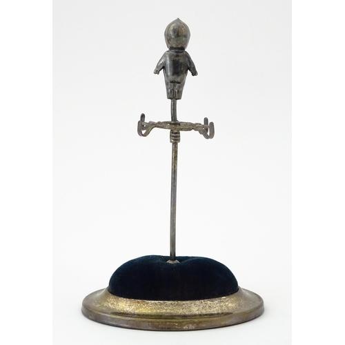 334 - A silver plate hat pin holder / ring tree surmounted by a model of a Kewpie doll. Marked with regist... 