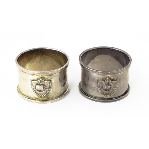 379 - A pair of Art Deco silver napkin rings with engine turned decoration and shield crest depicting boat... 