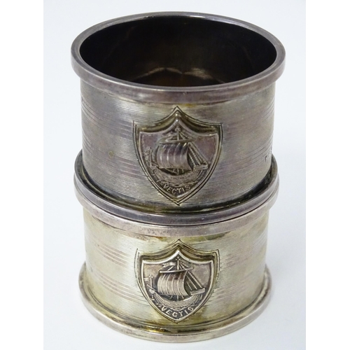 379 - A pair of Art Deco silver napkin rings with engine turned decoration and shield crest depicting boat... 