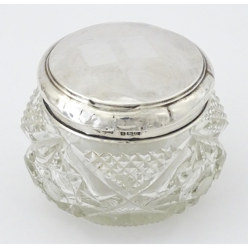 396 - A cut glass dressing table pot with silver lid hallmarked Birmingham 1923, maker Samuel M Levi. Appr... 