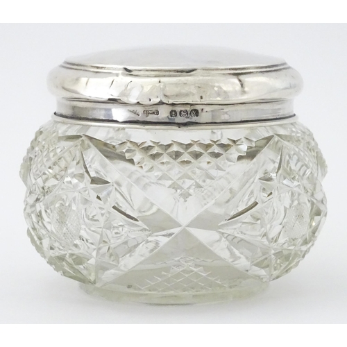 396 - A cut glass dressing table pot with silver lid hallmarked Birmingham 1923, maker Samuel M Levi. Appr... 