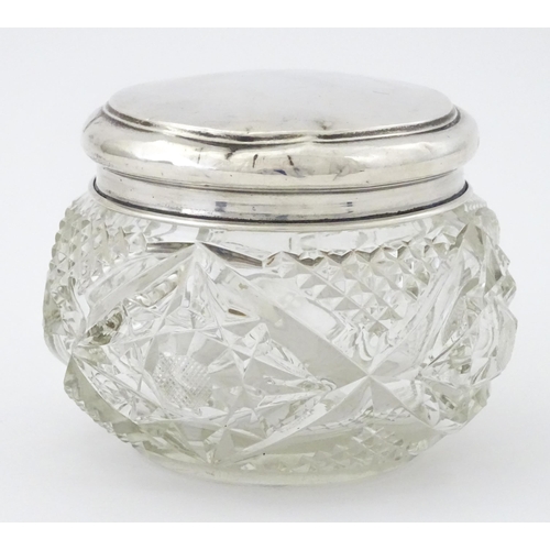 396 - A cut glass dressing table pot with silver lid hallmarked Birmingham 1923, maker Samuel M Levi. Appr... 