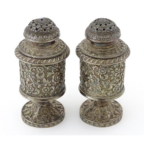 397 - A pair of white metal cruets / peppers of pedestal with floral and foliate decoration. Possibly Indi... 