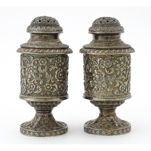 397 - A pair of white metal cruets / peppers of pedestal with floral and foliate decoration. Possibly Indi... 