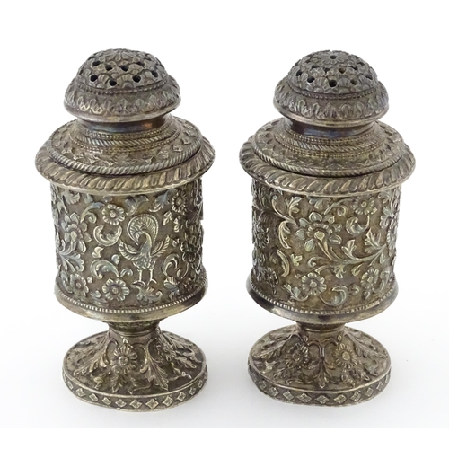 397 - A pair of white metal cruets / peppers of pedestal with floral and foliate decoration. Possibly Indi... 