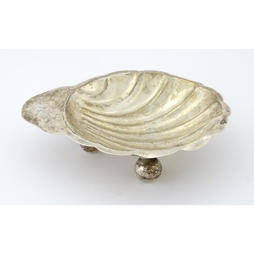 402 - A Mexican sterling silver butter dish of scallop shell form raised on three ball feet, by Juvento Lo... 