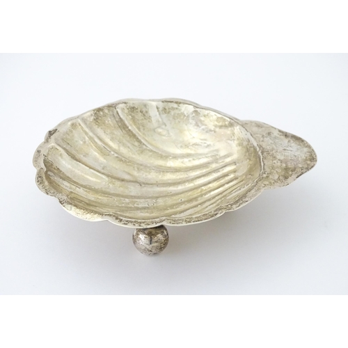 402 - A Mexican sterling silver butter dish of scallop shell form raised on three ball feet, by Juvento Lo... 