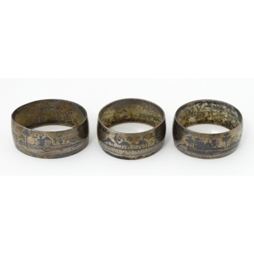 459 - Three white metal napkin rings with niello decoration depicting Egyptian scenes with camels, River N... 