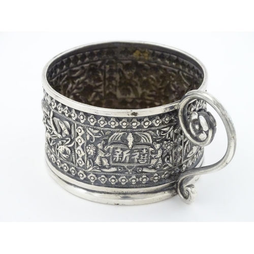 463 - An Oriental white metal tisane cup holder decorated with various panels depicting flowers, birds, cr... 