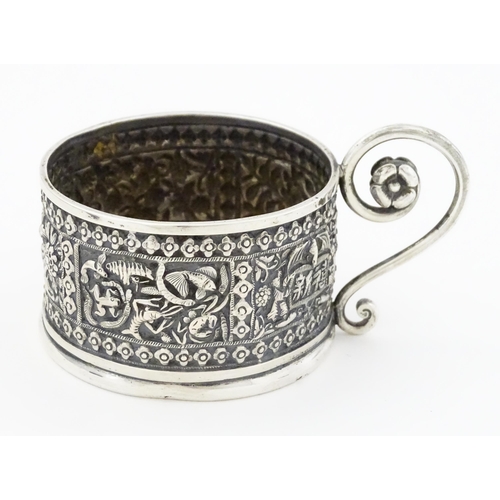 463 - An Oriental white metal tisane cup holder decorated with various panels depicting flowers, birds, cr... 