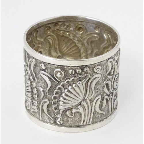 469 - A Continental white metal napkin ring  with floral and foliate detail, indistinctly marked to rim TO... 